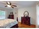 Bright bedroom featuring hardwood floors, ceiling fan, and coordinating dark wood dressers at 100 Willow Wood Road, Social Circle, GA 30025