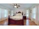 Bright bedroom featuring a wooden bed frame, a floral pattern bedspread, and two windows with white curtains at 100 Willow Wood Road, Social Circle, GA 30025