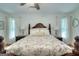 Bright bedroom featuring a wooden bed frame, a floral pattern bedspread, and two windows with white curtains at 100 Willow Wood Road, Social Circle, GA 30025