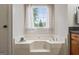 Bright bathroom featuring a soaking tub beneath a window with privacy curtains at 200 Pine Tree Ln, Mcdonough, GA 30252