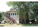Rear view of the house with two levels, a wooden stairway, trees, and patio furniture at 9342 Carillon Ct, Jonesboro, GA 30236