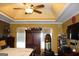 Primary bedroom featuring tray ceilings, hardwood floors, and a large television at 9342 Carillon Ct, Jonesboro, GA 30236