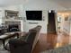 Bright living room with a brick fireplace, a large TV, and hardwood floors leading to the stairway at 521 Deadwood Trl, Locust Grove, GA 30248