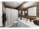 Stylish bathroom featuring a white vanity, decorative mirror, and shower with patterned curtain at 1504 Oglethorpe Dr, Suwanee, GA 30024