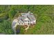 Expansive aerial shot of a light colored home and a long drive, complemented by vibrant landscaping and mature trees at 104 Hidden Springs Ln, Peachtree City, GA 30269