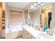 Bright bathroom featuring dual sinks, a soaking tub, and natural light from the window at 402 Stonebrooke Dr, Auburn, GA 30011