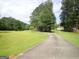 Curving driveway leading to a residence, surrounded by green lawns and mature trees at 3025 Ebenezer Rd., Se Rd, Conyers, GA 30094
