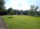 Expansive front yard with lush green grass and scattered mature trees on a sunny day at 3025 Ebenezer Rd., Se Rd, Conyers, GA 30094