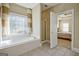 Primary bath features a soaking tub beneath a beautiful window and a view into the primary bedroom at 100 Clydesdale Ct, Tyrone, GA 30290