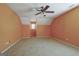A large bedroom with orange walls, a ceiling fan, and a window overlooking a picturesque outdoor view at 100 Clydesdale Ct, Tyrone, GA 30290