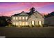 Charming two-story brick home with a manicured lawn and a covered front porch during a beautiful sunset at 6857 Louis Dr, Locust Grove, GA 30248