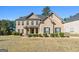 Beautiful two-story brick home featuring a well-maintained lawn, mature landscaping, and classic architectural details at 6857 Louis Dr, Locust Grove, GA 30248