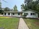 Charming one-story home with white exterior, dark shutters, mature trees, and green lawn at 125 Lafayette Dr, Fayetteville, GA 30214