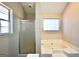 Bathroom with bathtub and shower featuring glass door, and a large window bringing in natural light at 701 Monticello Ln, Mcdonough, GA 30253