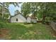 Backyard featuring green lawn, trees, a garden and a detached storage building with white siding and black trim at 203 First Leaf, Peachtree City, GA 30269