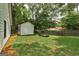 Backyard featuring green lawn, trees, a garden and a detached storage building with white siding and black trim at 203 First Leaf, Peachtree City, GA 30269