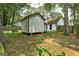 Backyard featuring green lawn, trees and a detached storage building with white siding and black trim at 203 First Leaf, Peachtree City, GA 30269