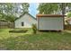 Backyard featuring green lawn, trees, a garden and a detached storage building with white siding and black trim at 203 First Leaf, Peachtree City, GA 30269