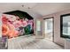 Bedroom featuring laminate flooring, pastel pink paint, and a decorative floral accent wall and backyard access at 203 First Leaf, Peachtree City, GA 30269