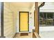 Close-up of a bright yellow front door with black trim and a welcome mat at 203 First Leaf, Peachtree City, GA 30269