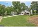 A charming white bungalow with lush landscaping, mature trees, and a well-maintained lawn at 203 First Leaf, Peachtree City, GA 30269