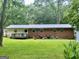 View of the back of a brick home with a lawn, deck, and mature trees, providing a private outdoor space at 3683 Miller St, Lithia Springs, GA 30122