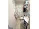 Compact bathroom featuring a shower with curtain, pedestal sink, toilet, and essential storage shelving at 3683 Miller St, Lithia Springs, GA 30122
