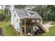 Rear elevation view of a white, two-story house featuring an upper deck with stairs to a concrete patio at 10 Stagg Trce, Social Circle, GA 30025