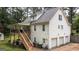Rear view of a white two-story home featuring an upper deck, outdoor stairway, and a three-car garage at 10 Stagg Trce, Social Circle, GA 30025