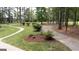 Well-manicured yard with sidewalk winding through landscaped beds and mature trees surrounding property at 10 Stagg Trce, Social Circle, GA 30025
