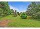 Large backyard featuring mature trees, shrubbery, and a large grassy area at 4547 Atha Cir, Loganville, GA 30052