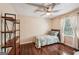Bright bedroom features hardwood floors, neutral paint, a ceiling fan, and a large window with natural light at 10875 Shagbark Trl, Roswell, GA 30075