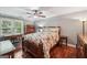 Cozy bedroom features hardwood floors, a ceiling fan, neutral paint, and a large window with outdoor views at 10875 Shagbark Trl, Roswell, GA 30075