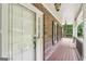 Inviting covered front porch featuring brick accents, wood flooring, and charming hanging lights at 10875 Shagbark Trl, Roswell, GA 30075