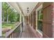 Inviting covered front porch featuring brick accents, wood flooring, and charming hanging lights at 10875 Shagbark Trl, Roswell, GA 30075