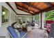 Inviting covered porch with wooden ceiling and floors features seating, a fireplace, and views of the surrounding landscape at 10875 Shagbark Trl, Roswell, GA 30075