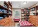 Walk-in closet with custom wooden storage, shelving, a window and ruby-red bench at 10875 Shagbark Trl, Roswell, GA 30075