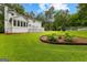 Expansive backyard featuring lush green grass, a beautiful flower bed, and a charming white house at 607 Lees Mill Rd, Fayetteville, GA 30214