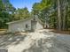 Large detached garage with multiple doors and a gravel driveway, surrounded by trees at 607 Lees Mill Rd, Fayetteville, GA 30214