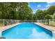 Refreshing in-ground swimming pool surrounded by a white fence, lounge chairs, and lush trees at 607 Lees Mill Rd, Fayetteville, GA 30214