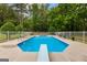 Beautiful in-ground pool with diving board surrounded by a white fence and lush trees at 607 Lees Mill Rd, Fayetteville, GA 30214