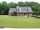 Charming brick home with a lush green lawn and inviting front porch nestled among mature trees at 500 Hayfield Ct, Locust Grove, GA 30248