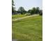 Open green yard with a dirt path leading up to a street with cars and houses in the distance at 619 E College St, Bowdon, GA 30108