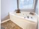 Large soaking tub next to window in bathroom with neutral color palette at 329 Royal Crescent Way, Stockbridge, GA 30281