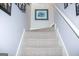 Carpeted staircase with white railing leads to the upper level, complemented by decorative wall art at 329 Royal Crescent Way, Stockbridge, GA 30281