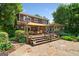 Charming back exterior featuring a spacious deck, stone patio, and lush landscaping at 99 Landers Ne Rd, Rydal, GA 30171