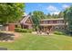 A charming home exterior features a stone patio with lush landscaping and a covered deck at 99 Landers Ne Rd, Rydal, GA 30171