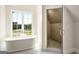 Bright bathroom featuring a soaking tub beneath a window and a glass-enclosed shower with tile surround at 100 Regina Ct, Fayetteville, GA 30215