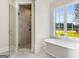 Modern bathroom with tiled shower and freestanding soaking tub next to large window with natural views at 100 Regina Ct, Fayetteville, GA 30215