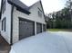 Side view of the three car garage, with painted doors, brick facade, and spacious concrete driveway at 100 Regina Ct, Fayetteville, GA 30215